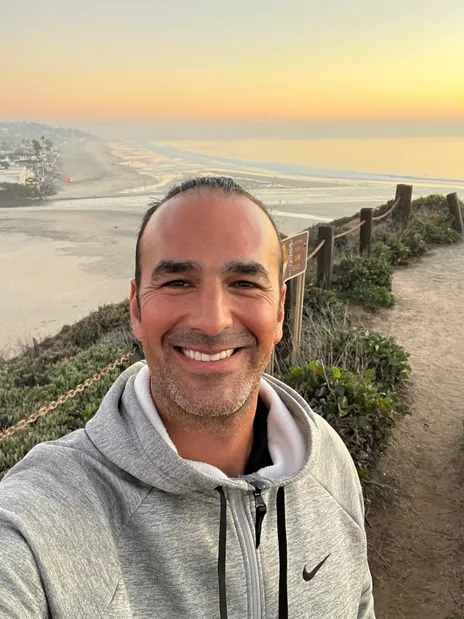 Alan Seideman, outdoors on a bluff above the beach at sunset
